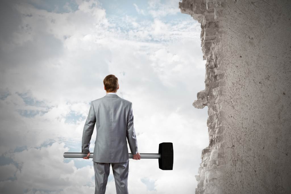 Business leader facing a wall with a sledgehammer, symbolising the effort to break through enterprise architecture challenges.